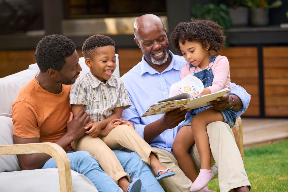 Senior man with his son and grandchildren reading a book 